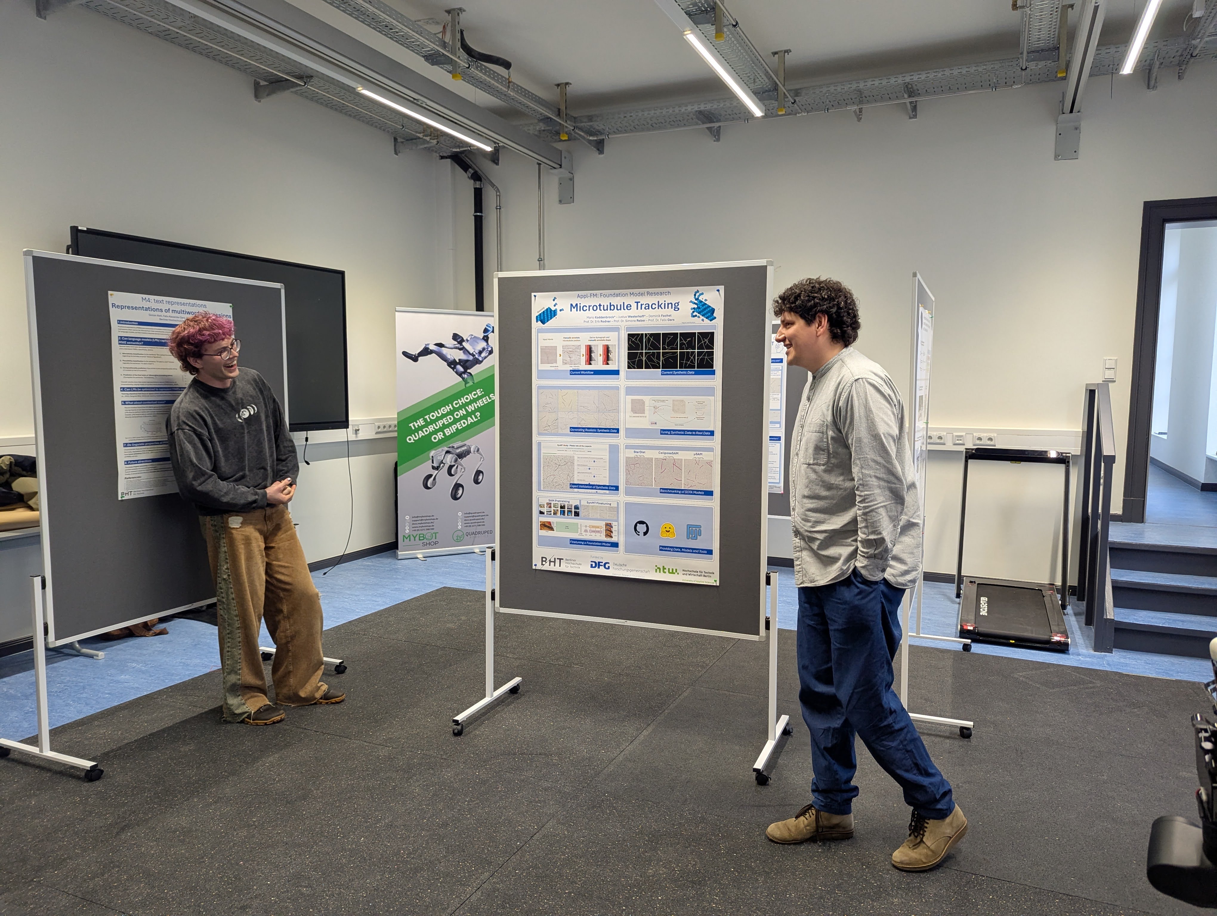 Two researchers talking in front of a poster on microtubule tracking